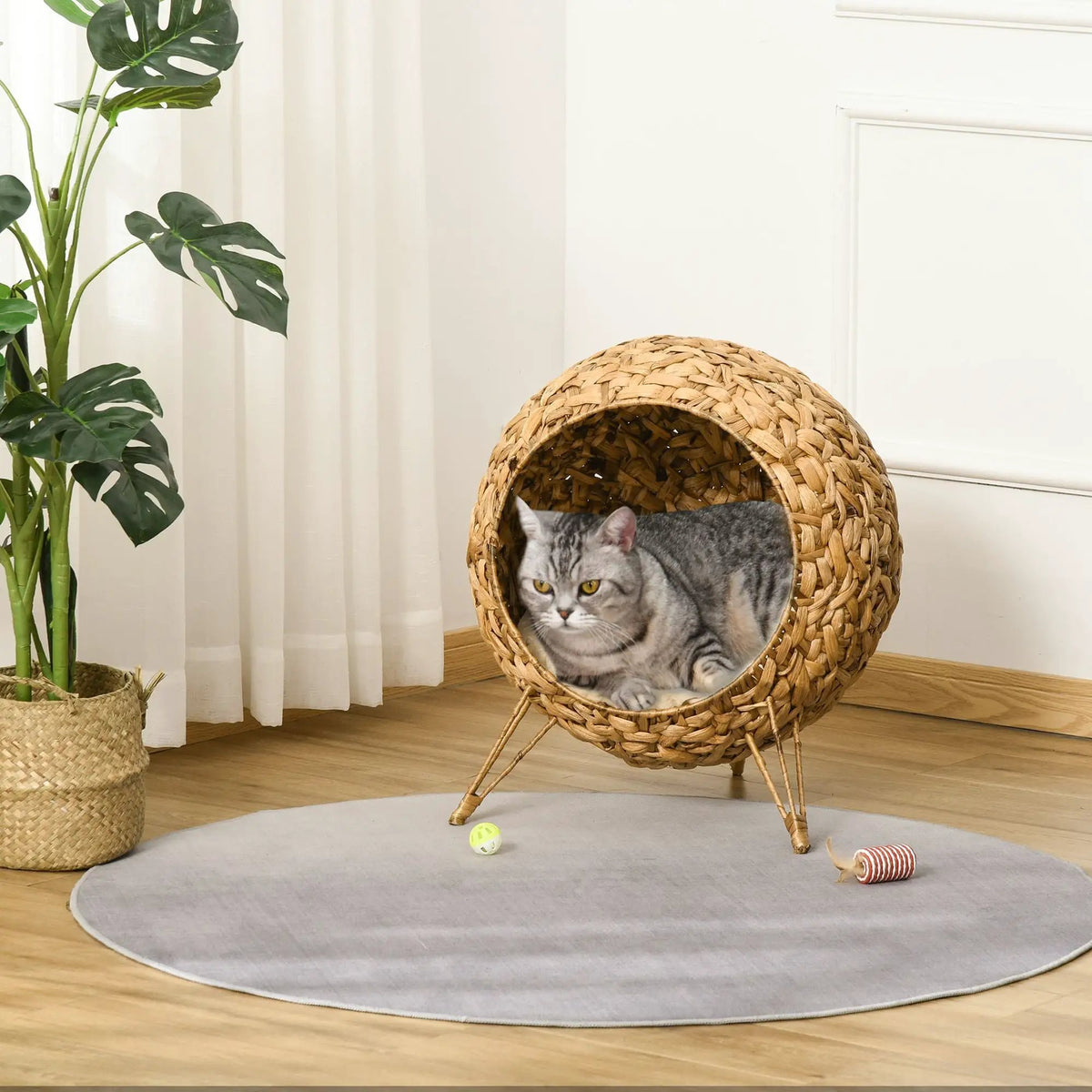 Doba Cozy Elevated Cat Bed: brown handcrafted woven cat condo with soft cushion and cat inside.