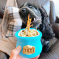 Load image into Gallery viewer, Chicken feet dog treats in a bright blue bowl; two feet protrude as a black dog sniffs.
