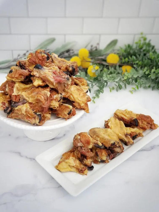 Chicken wings and drumettes, golden brown roasted, piled on a white pedestal and a rectangular plate.