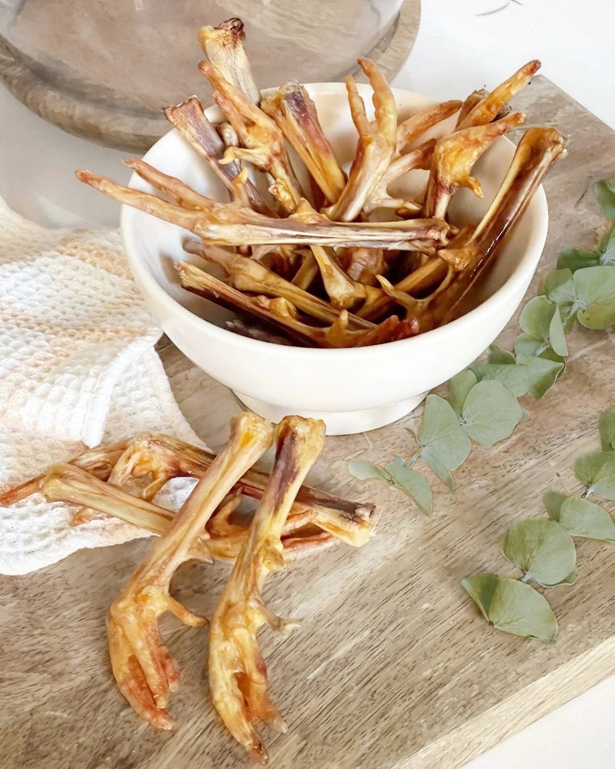 Pheasant Feet, dried amber-brown feet in a white bowl on a wooden table; multiple pieces