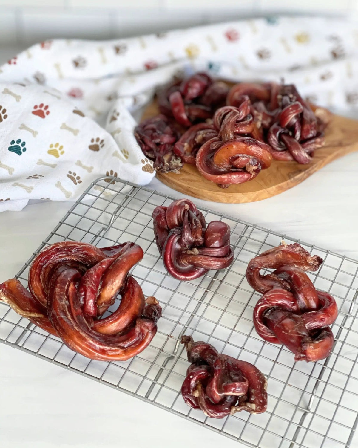 Limited Edition Beef Pizzle chews by Naked Beasts; sticks and loops in red dried form on a wooden board.