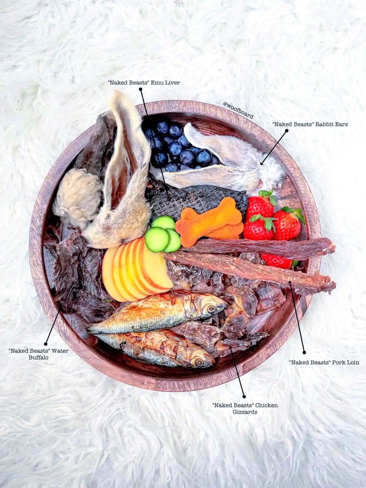 Naked Beasts Chicken Gizzards on round wooden platter with assorted meats and berries