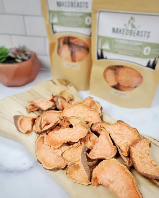 Sweet potato slices from Naked Beasts on a wooden board with beige Naked Beasts packaging in the background.
