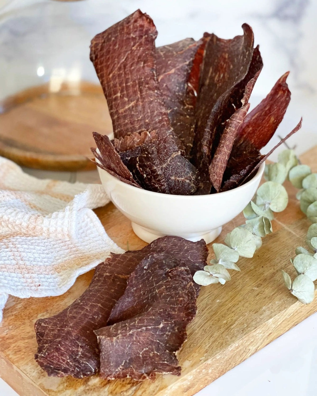 Angus beef jerky thin-cut by Naked Beasts, dark red slices in a white bowl
