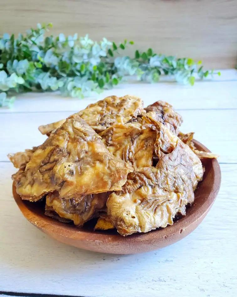 Pork brain by Naked Beasts, sliced pieces in a clay bowl on a light backdrop with greenery.