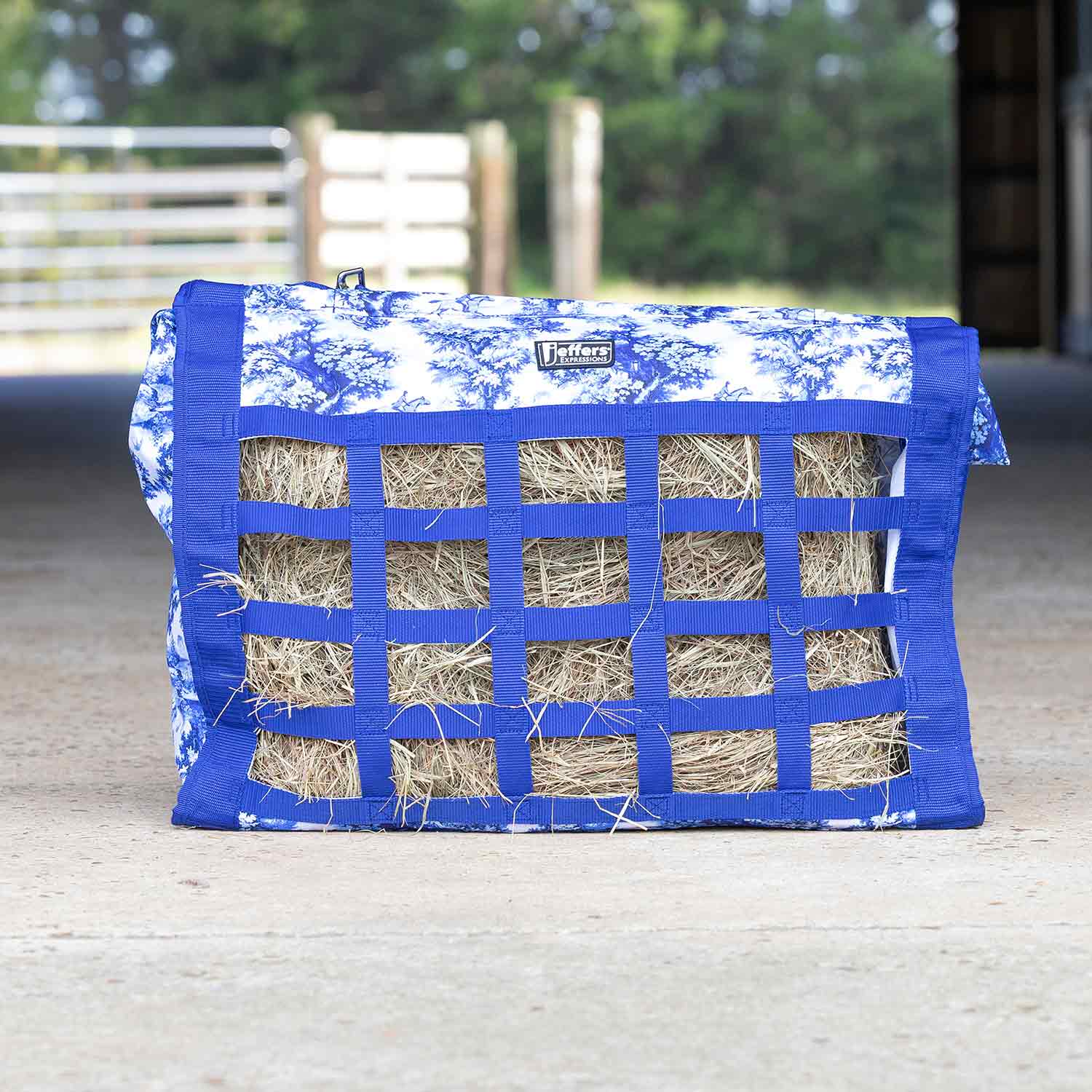Jeffers Expressions Extend-Feed hay bag for horses and livestock, blue fabric with square strap grid and visible hay.