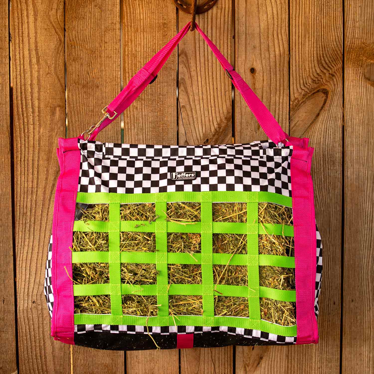 Jeffers Expression Extend-Feed hay bag for horses and livestock with pink straps and neon green grid, hay visible.