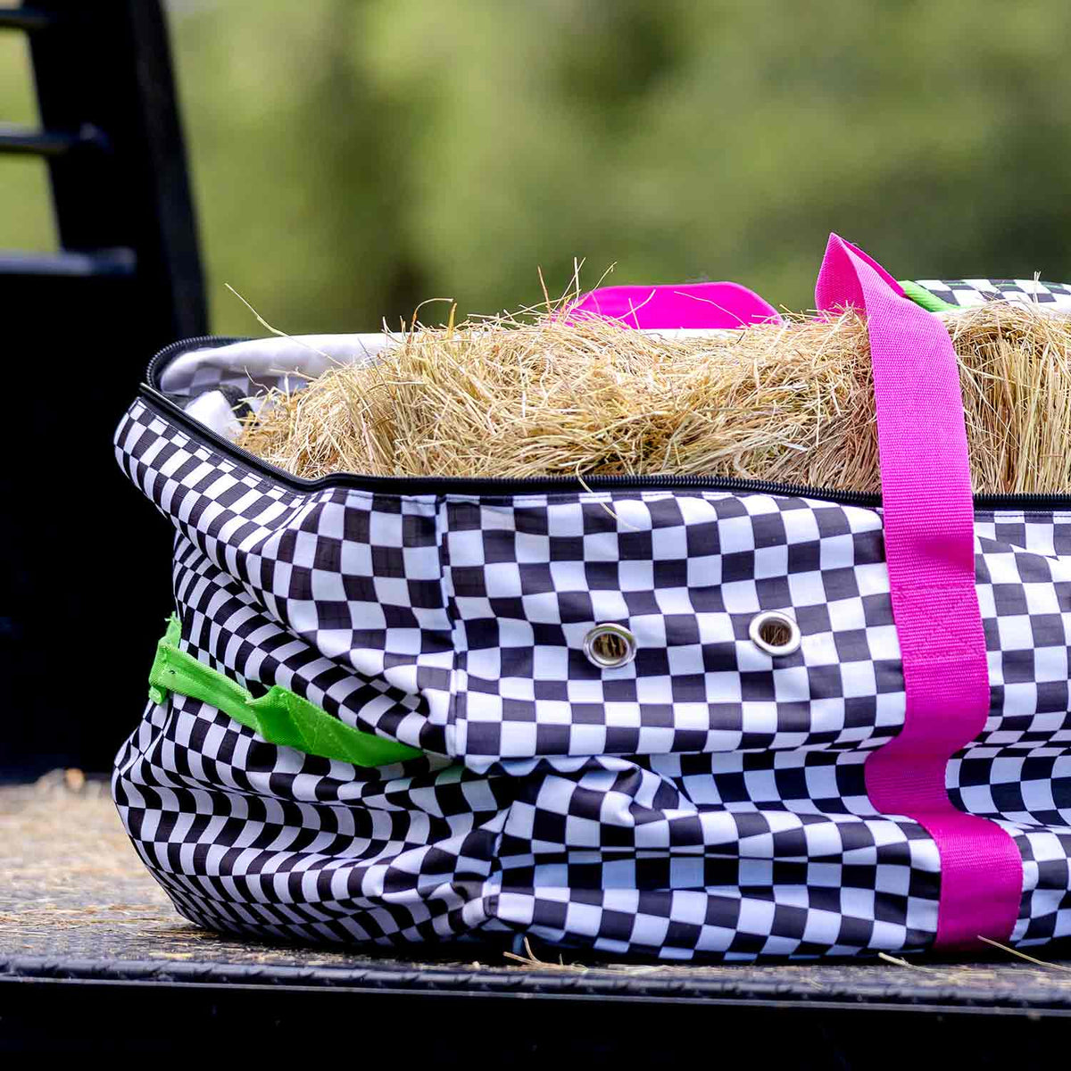 Jeffers Expression Full Hay Bale Tote Bag, black-and-white checker pattern with bright pink handles, filled with hay.