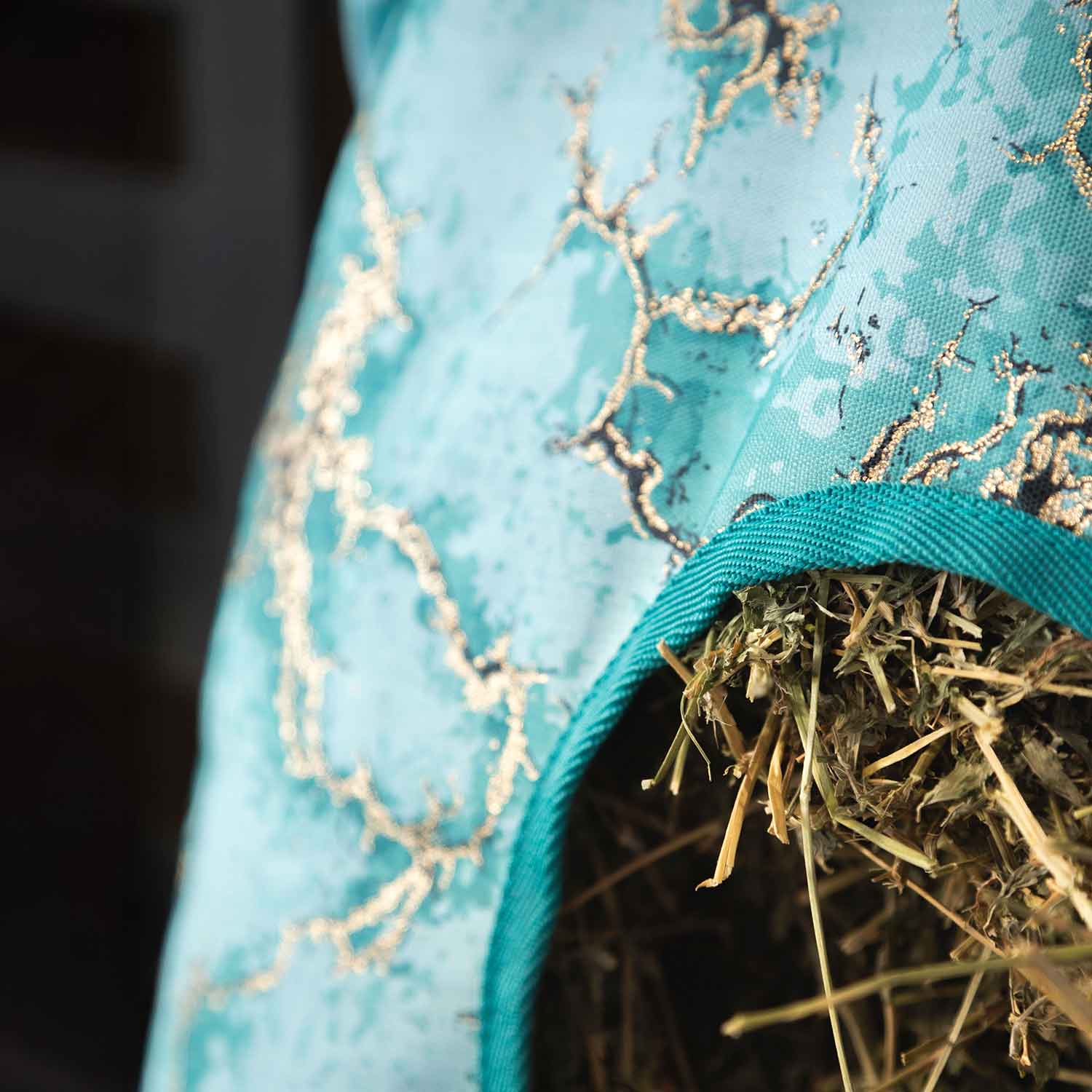 Jeffers Expression top-loading hay bag, 600 Denier, teal fabric with teal strap and visible hay spilling out