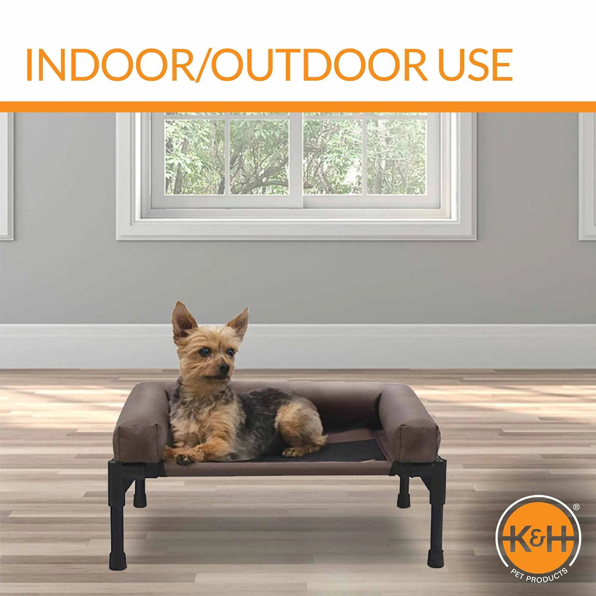 K&H Original Bolster Pet Cot Elevated Pet Bed in brown, small dog seated.