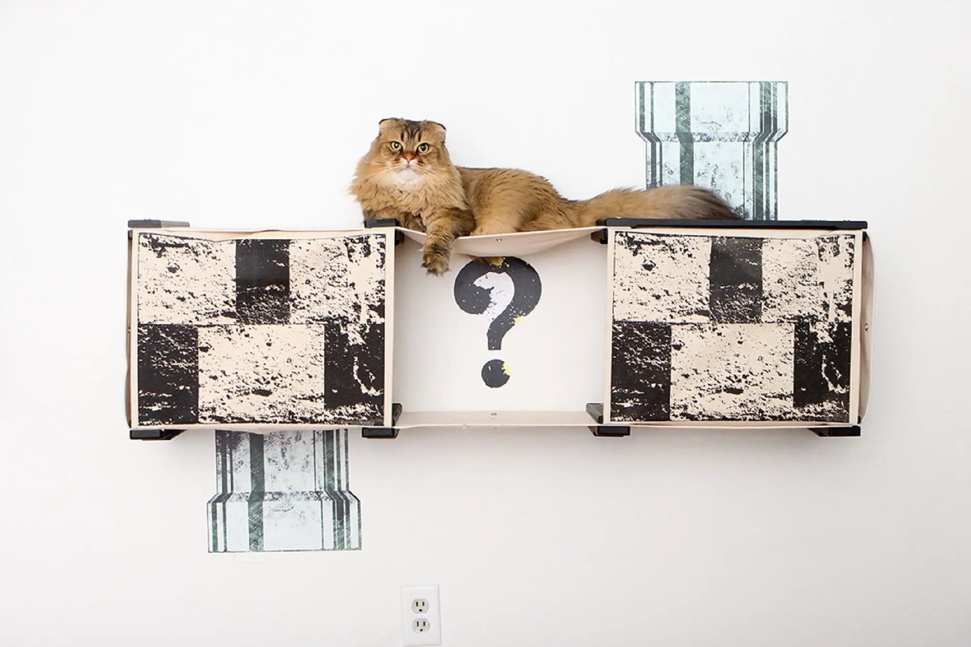 Super Mario Cat Tree cat condo by Catastrophic Creations, cat lounging on a hammock between patterned storage cubes.
