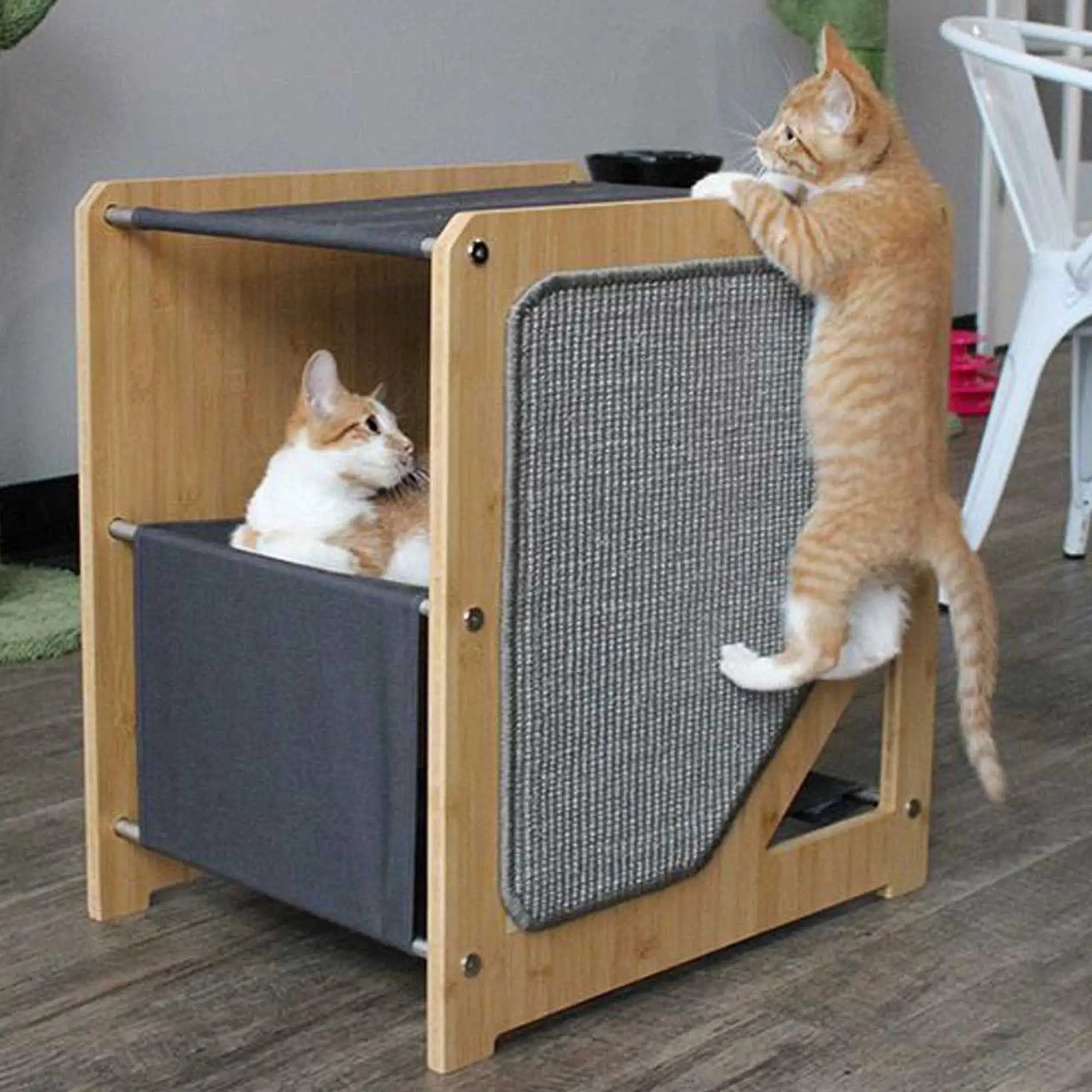 The Grotto cat tree for small spaces; wooden cat condo with dark fabric panels, orange cat climbing.
