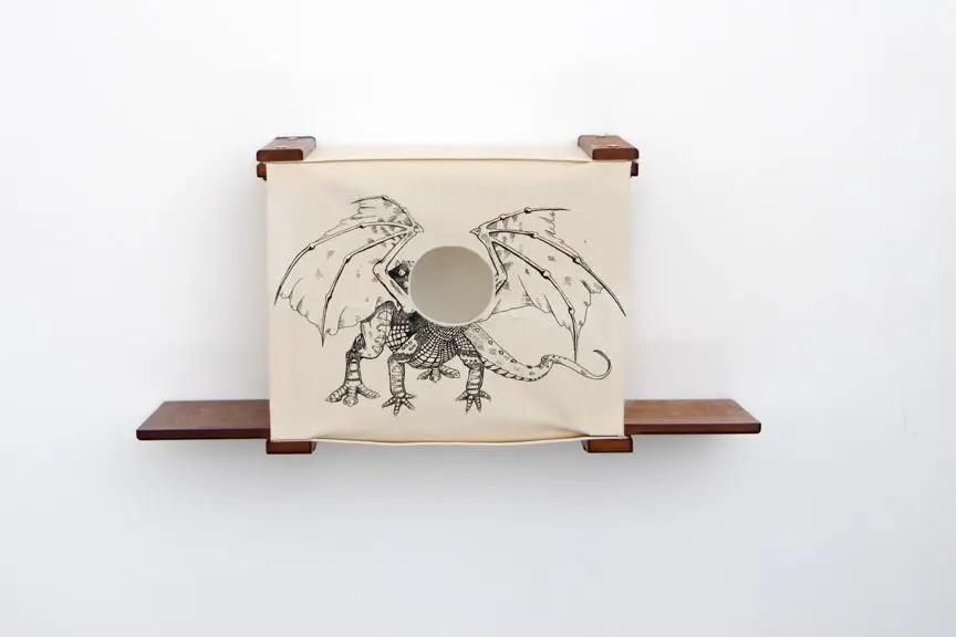 Cat Cubby for Wall Covered Cat Bed by Catastrophic Creations, beige fabric cube with dragon art and round entry hole.