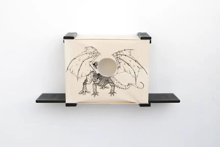 Cat Cubby for Wall - Covered Cat Bed; beige fabric cubby with dragon print and circular opening, wall-mounted.