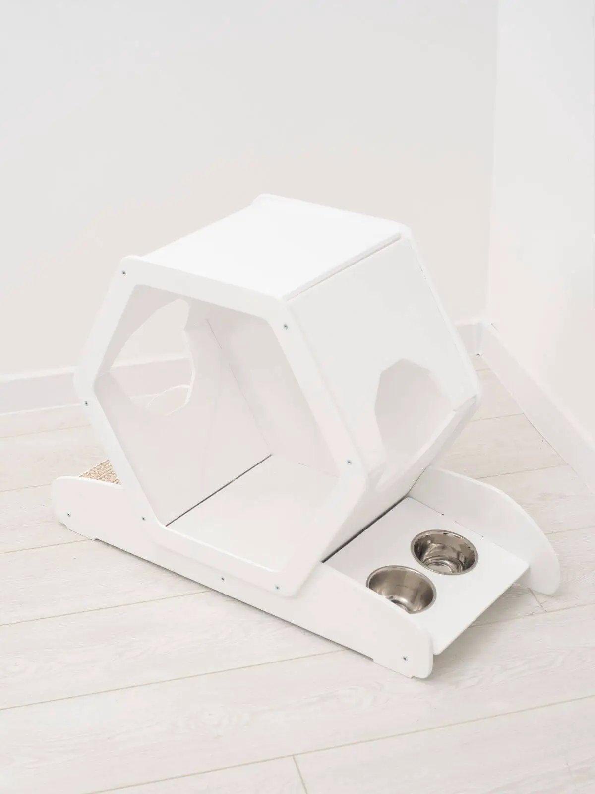 Small white wooden cat house with built-in dual metal bowls.