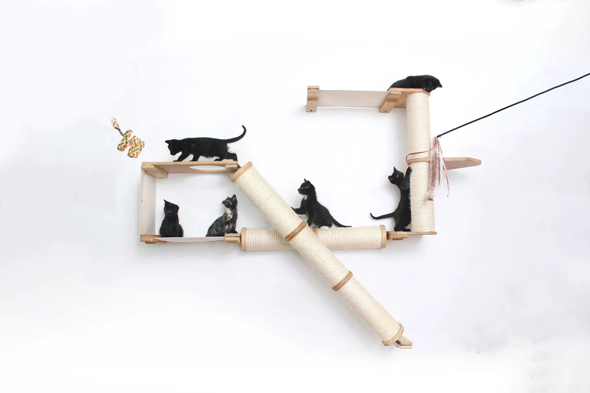 The Crossroads cat condo wall scratcher tree with ramp; natural wood and sisal rope, several black cats climbing.